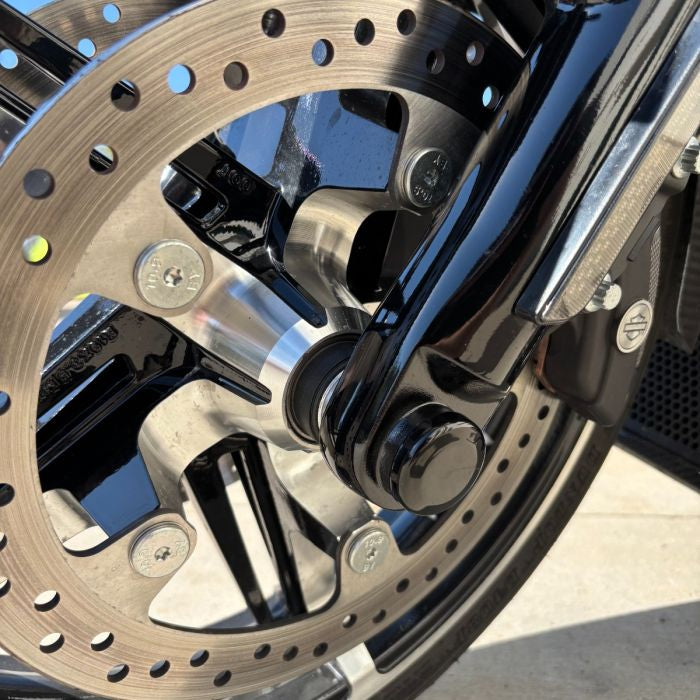 Black HOGWORKZ® Front Axle Covers for Harley® Touring on black bike